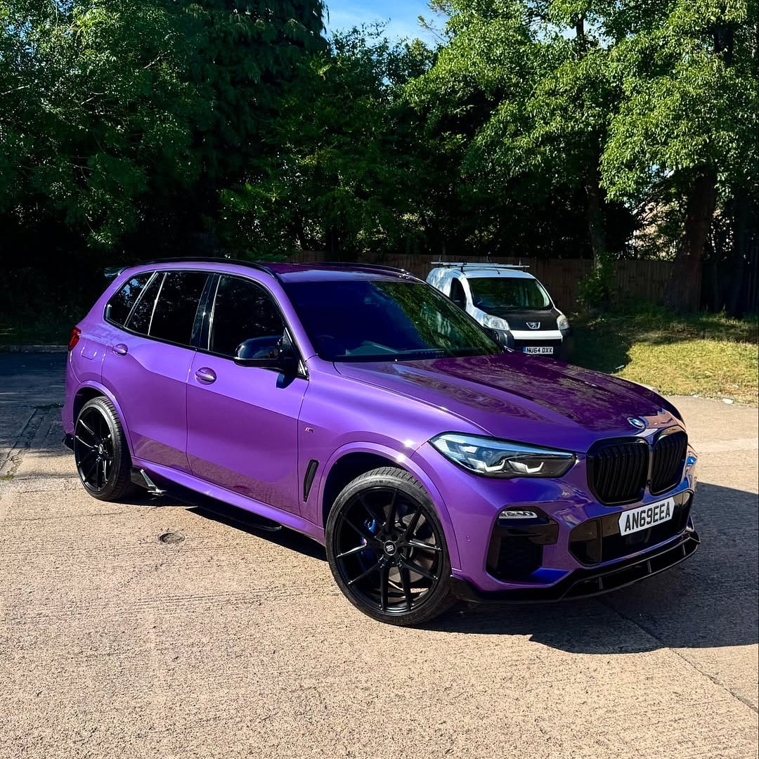 Oracal Gloss Violet Metallic wrap on a BMW SUV, parked on a driveway with trees