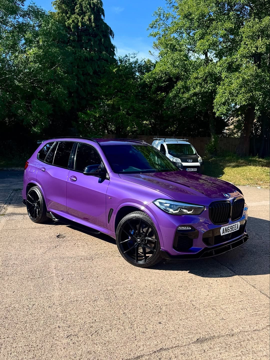 Oracal Gloss Violet Metallic wrap on a BMW SUV, parked on a driveway with trees