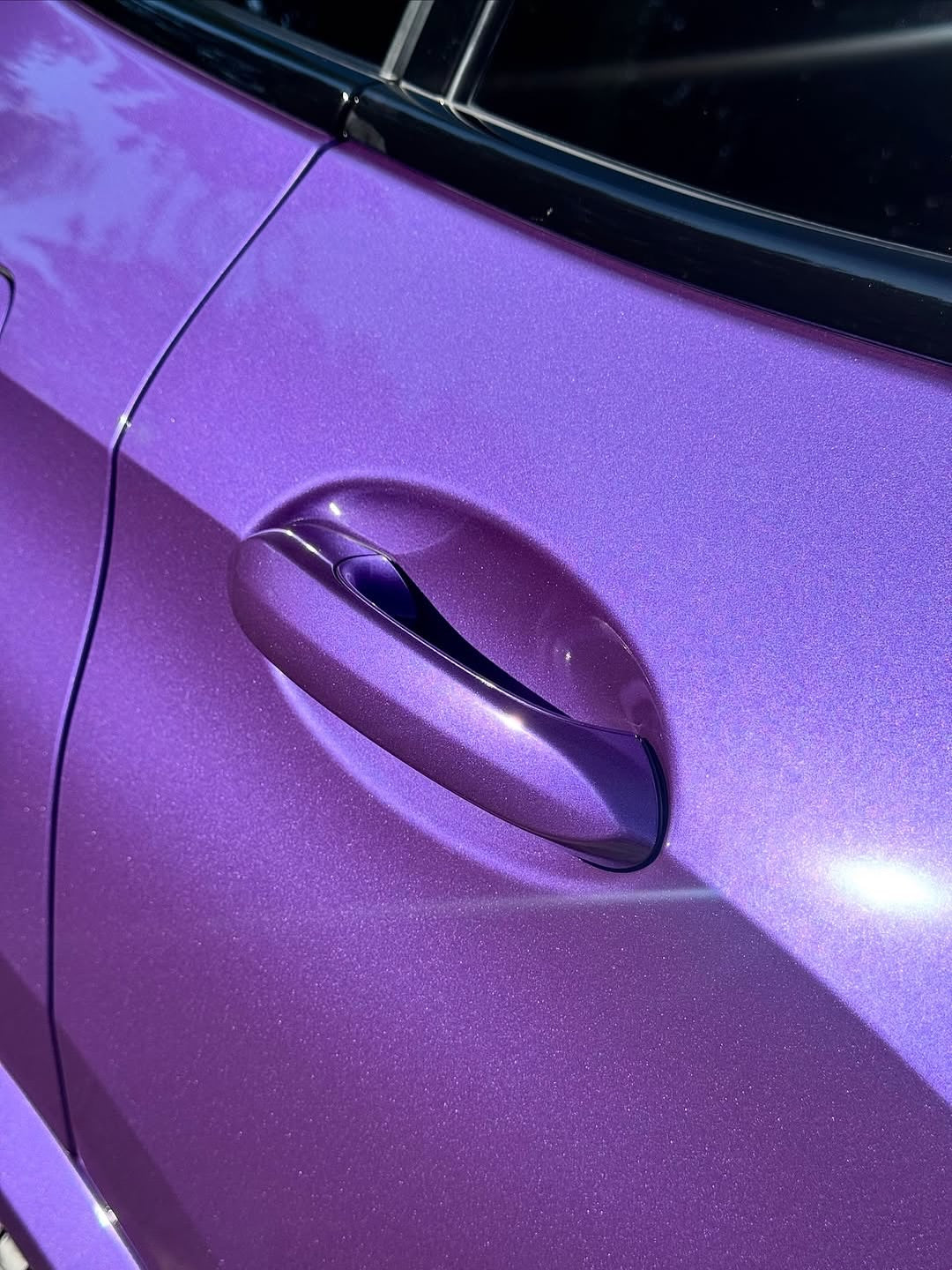 Close-up of a car door handle with Oracal Gloss Violet Metallic wrap installed