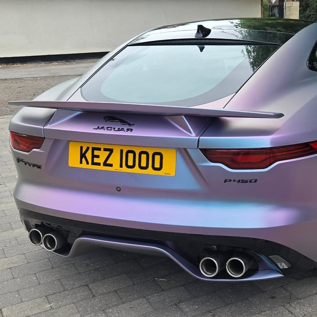 Oracal Matte Amethyst Jaguar car with a yellow license plate on a driveway