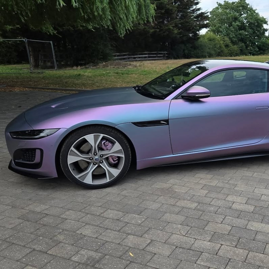 Luxury car with Oracal Matte Amethyst wrap on a paved surface with greenery