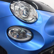 Close-up of an Oracal Matte Azure Blue Metallic car's headlight and grille