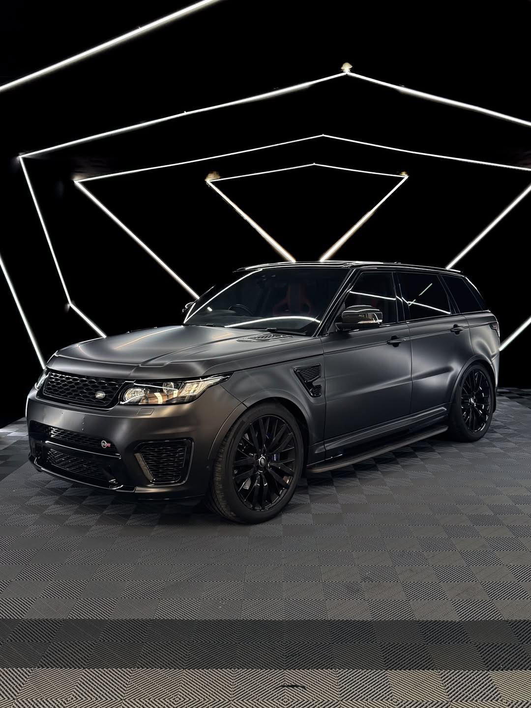 Oracal Matte Black installed on an SUV on a dark checkered floor with geometric light design