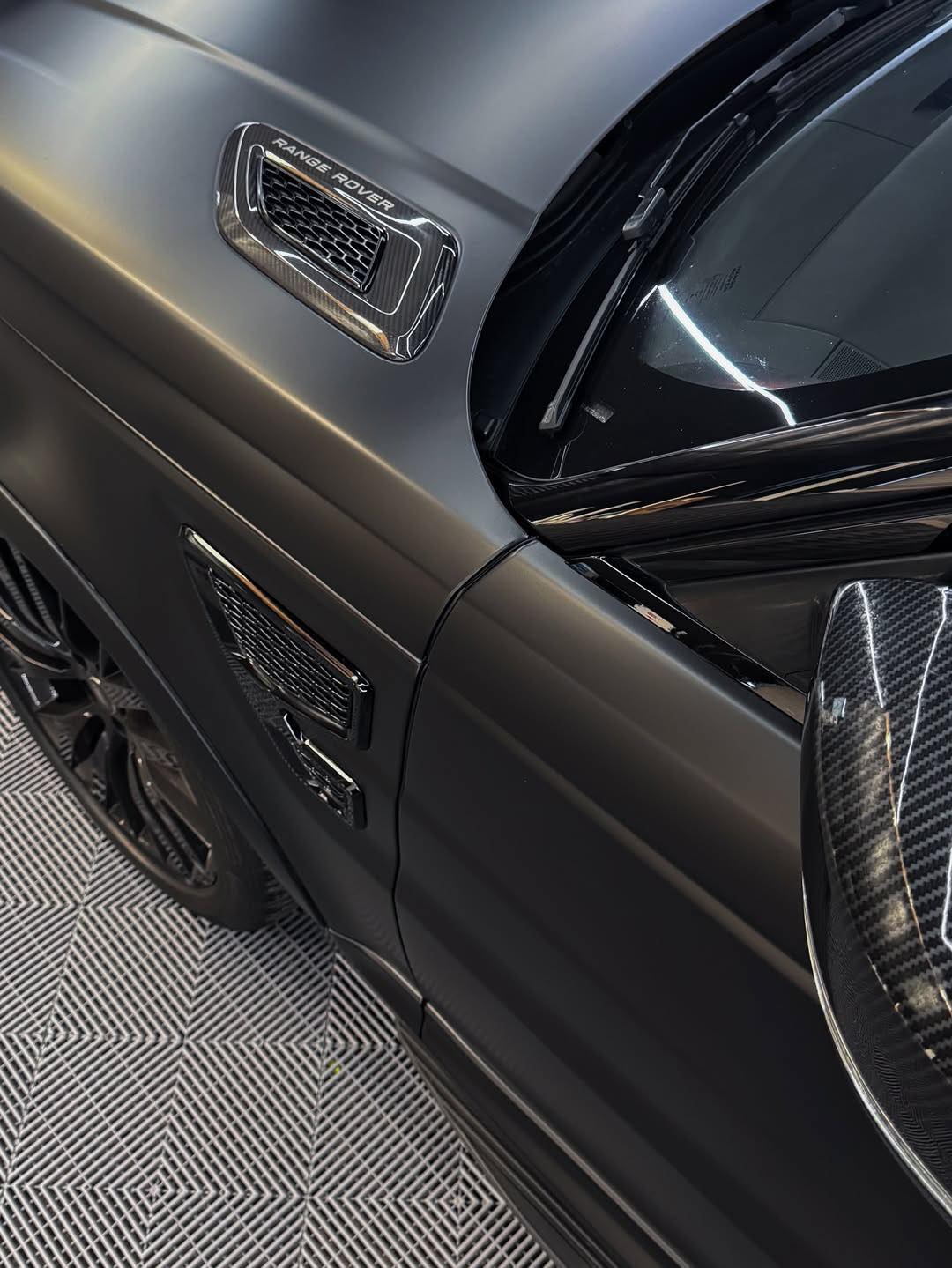 Close-up of an Oracal Matte Black installed on a car door with a visible badge on a patterned floor