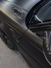 Close-up of an Oracal Matte Black installed on a car door with a visible badge on a patterned floor