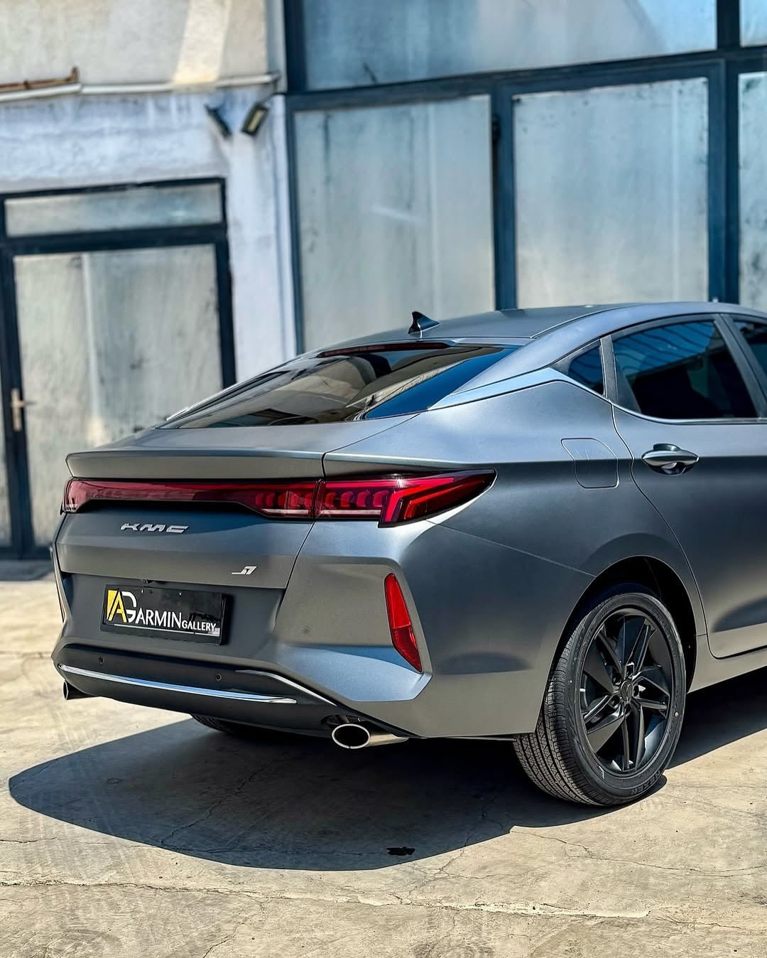 Oracal Matte Charcoal Metallic wrap installed on a car parked in front of a building with a clear sky