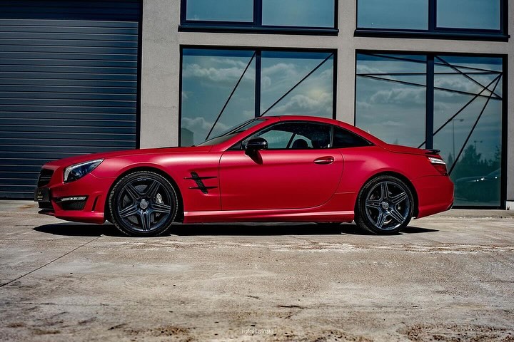 Oracal Matte Dark Red Metallic sports car parked in front of a modern building with large windows