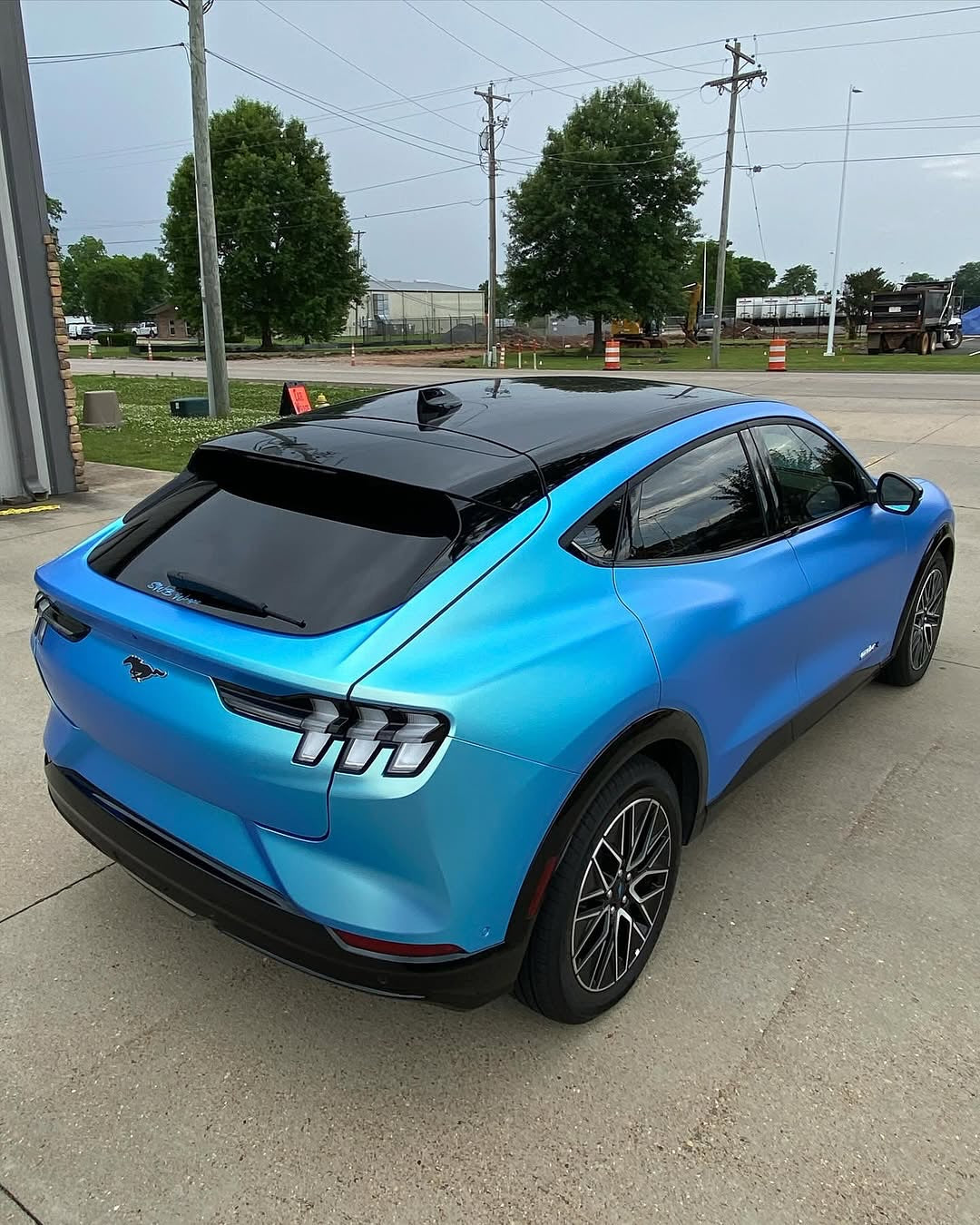 Oracal Matte Green Blue installed on a Ford Mustang parked on a concrete surface with trees and power lines