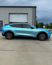 Oracal Matte Green Blue installed on a Ford Mustang parked in front of a building with a cloudy sky
