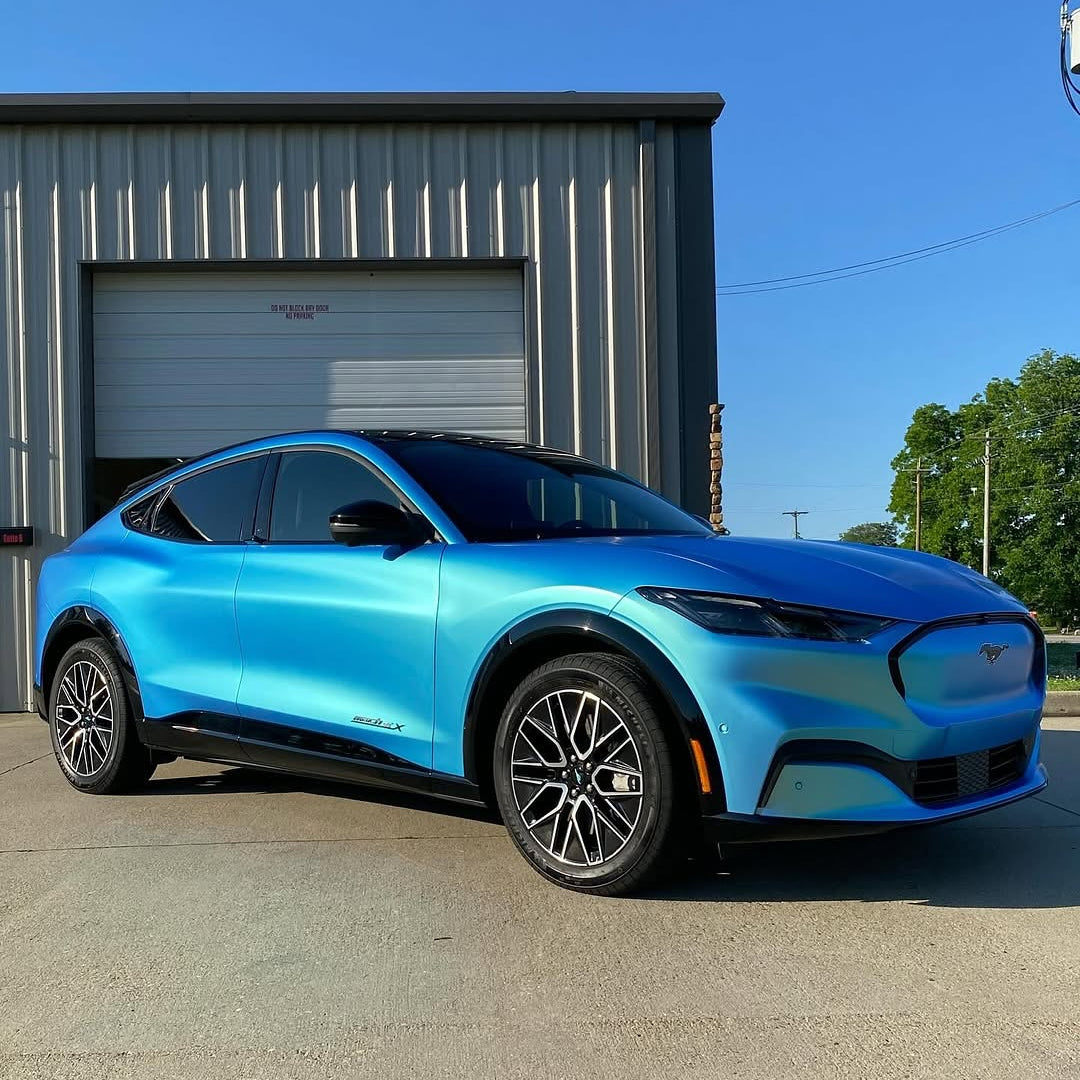 Oracal Matte Green Blue installed on a Ford Mustang parked in front of a building with a clear blue sky