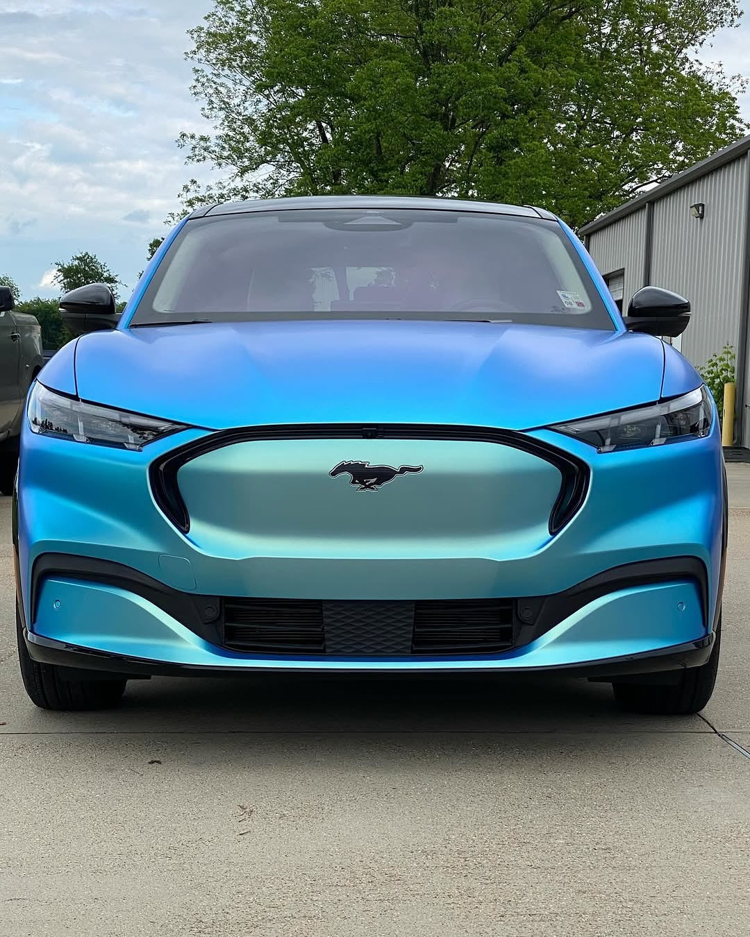 Oracal Matte Green Blue installed on a Ford Mustang Mach-E electric vehicle parked outdoors with trees and a building