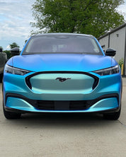 Oracal Matte Green Blue installed on a Ford Mustang Mach-E electric vehicle parked outdoors with trees and a building