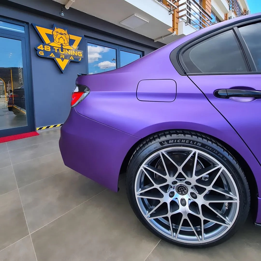 Oracal Matte Violet Metallic car with a Michelin tire in front of a garage