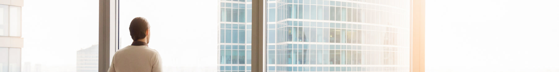 Specialist window film installed on large windows and an office worker looking out of the windows