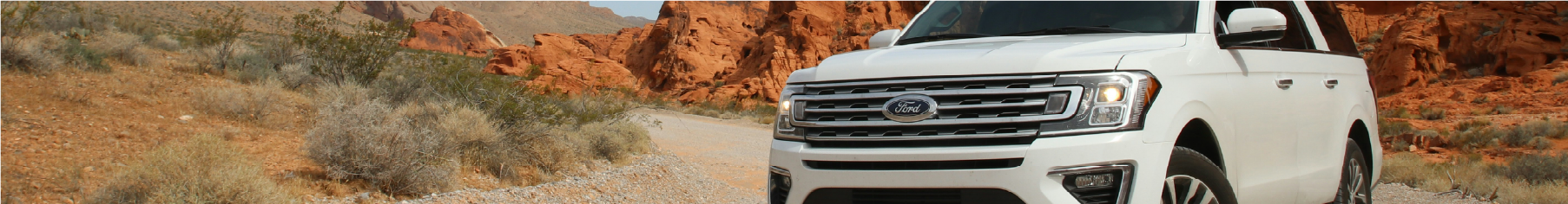 White Ford with Ford window tints installed in a desert landscape with red rock formations