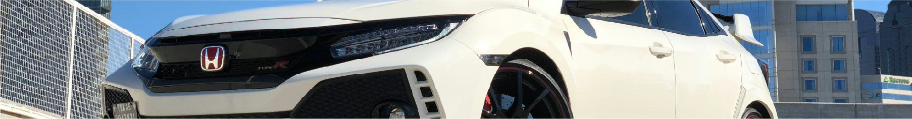 Cropped photo of a white Honda with a blue sky and buildings in the background after having Honda window tints installed