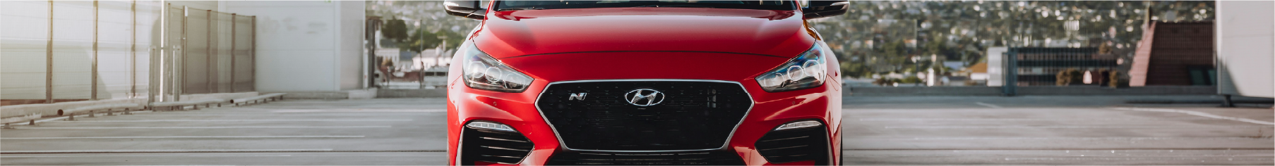 Cropped photo of a red Hyundai SUV on a rooftop with a cityscape background after having Hyundai window tints installed