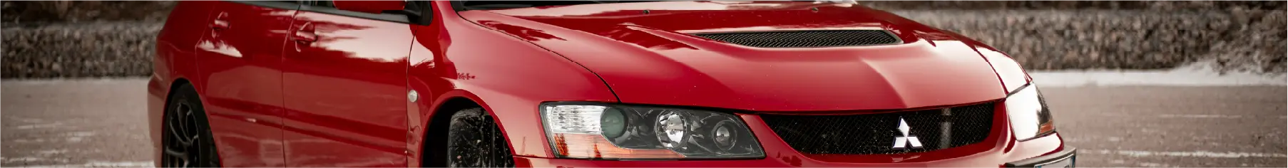 Red mitsubishi with newly installed Mitsubishi window tints parked outdoors