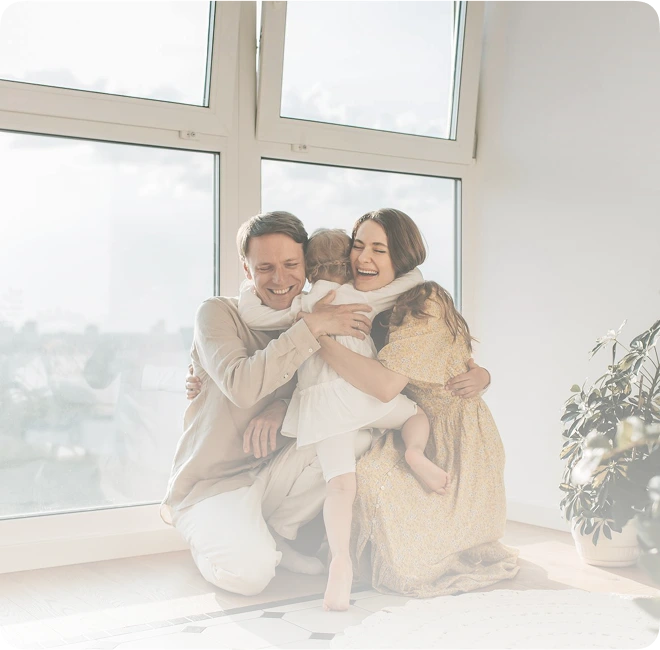 Family of three sitting together in a bright room with large windows with window film installed