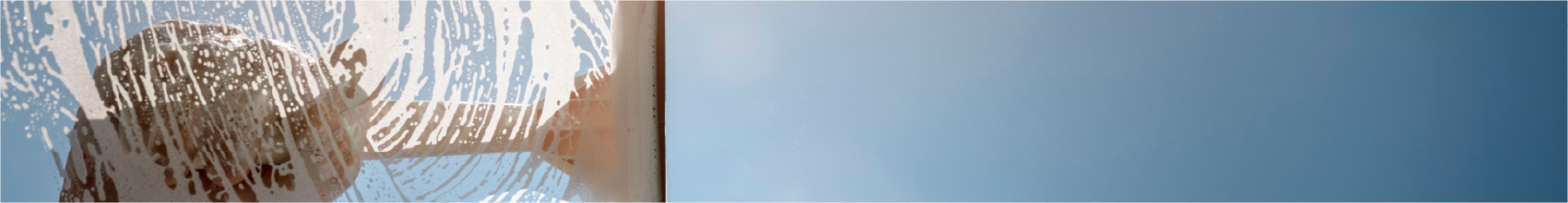 Close up of professional window squeegee and a hand washing soapy water from a window